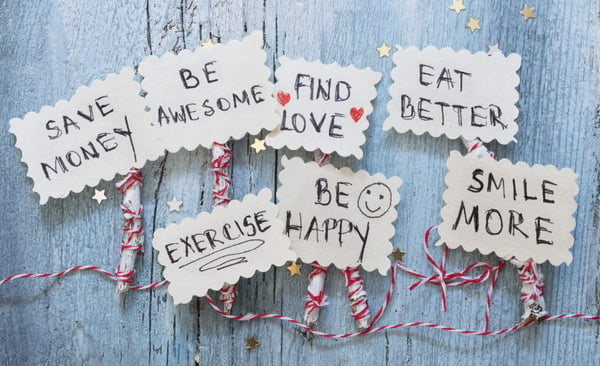 cutout photos on red and white twine saying resolutions like, save money, smile, be awesome, eat better, exercise, be happy, find love