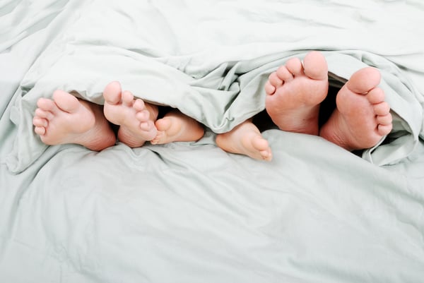Happy familiy in bed under sheet