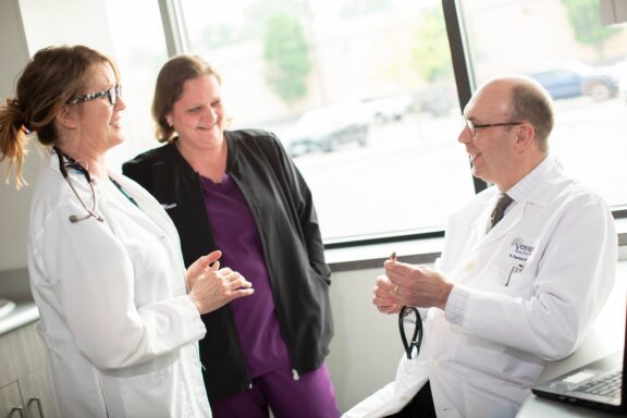 Healthcare professionals at Voyage Healthcare sharing a lighthearted conversation, fostering a collaborative and friendly clinical environment.