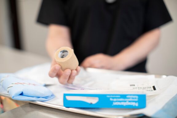 A healthcare professional holds medical wrap and other supplies prepared for podiatric care, highlighting readiness for foot and ankle treatments.