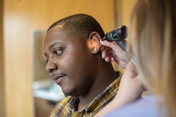 Man having his ear examined with an otoscope during a clinic visit.